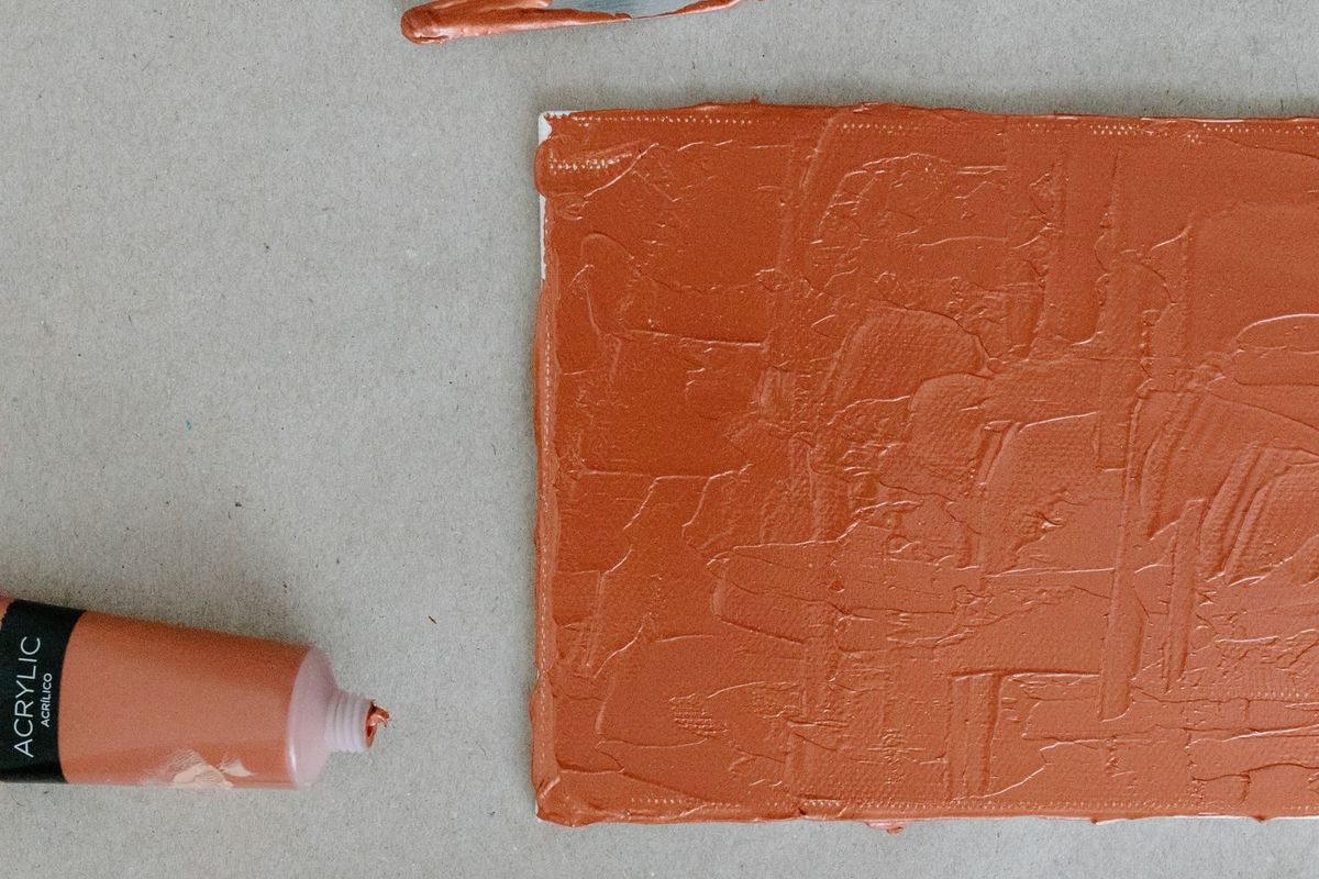 Pinceaux et couteau à peindre posés près d'un aplat de couleur